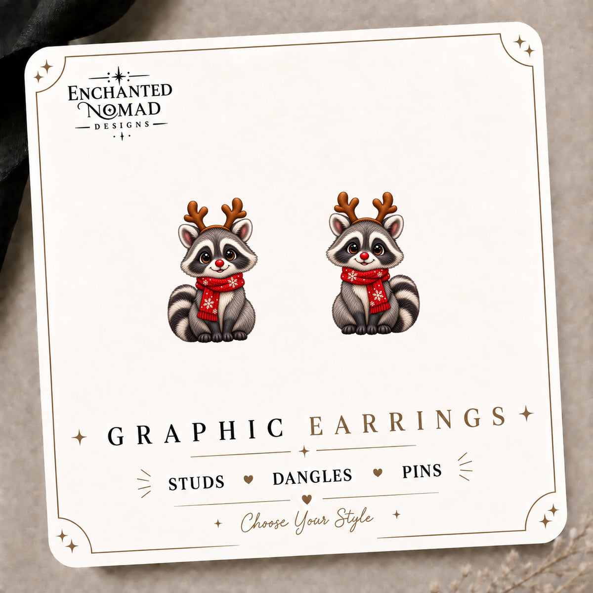 Cartoon Reindeer Raccoon Stud Earrings on the tilted Enchanted Nomad Designs card