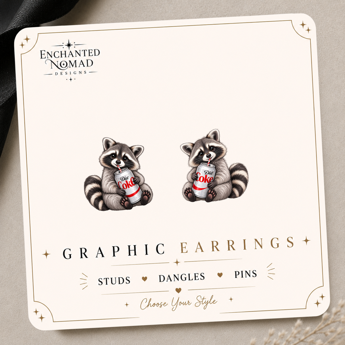 Raccoon holding a Diet Coke can, shown as a pair on the tilted Enchanted Nomad Designs display card