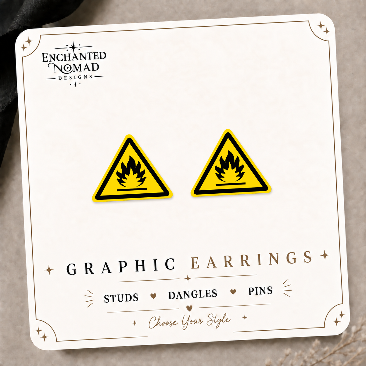 Yellow and black flammable warning sign earrings on an Enchanted Nomad Designs display card