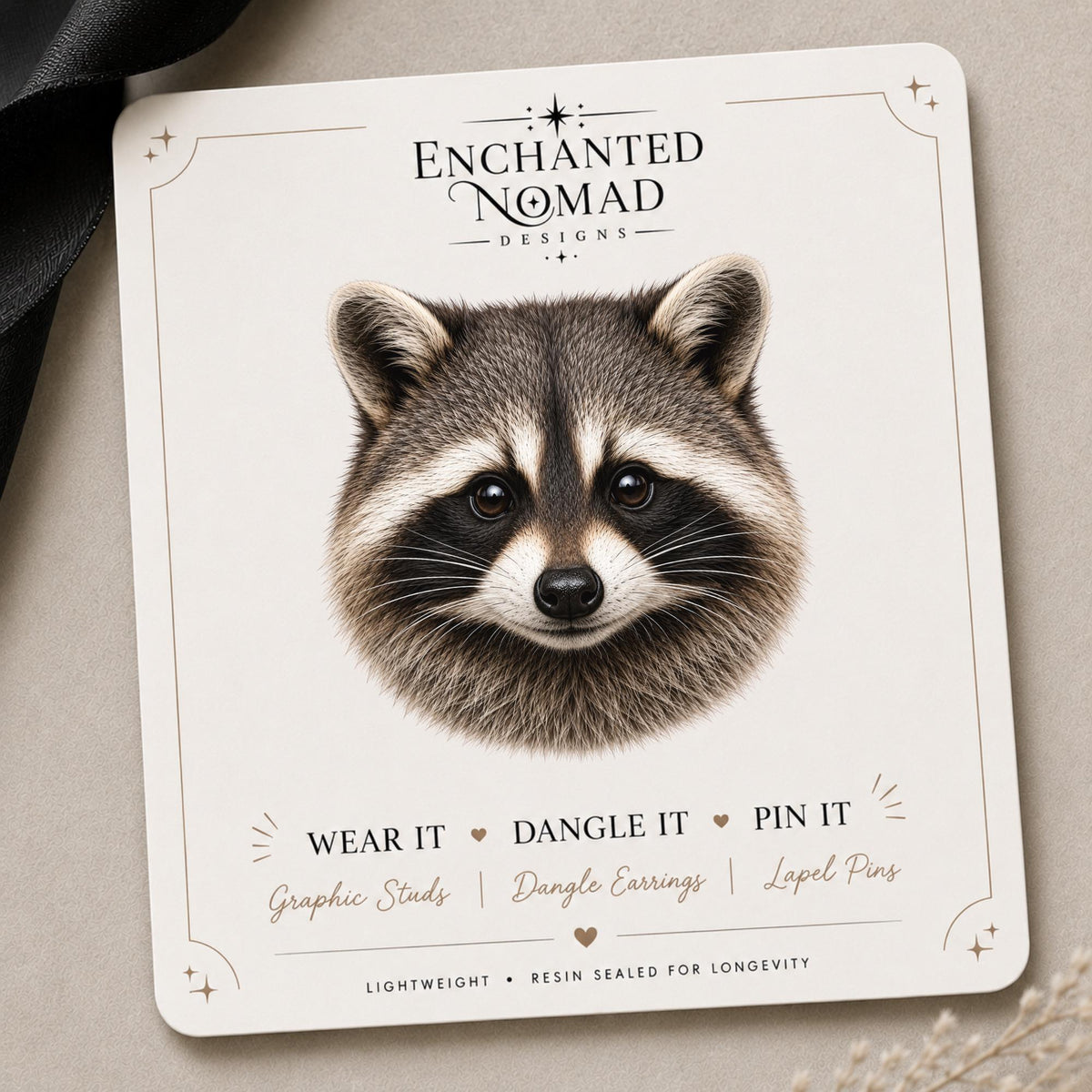 Raccoon Earrings & Pins on a branded display card