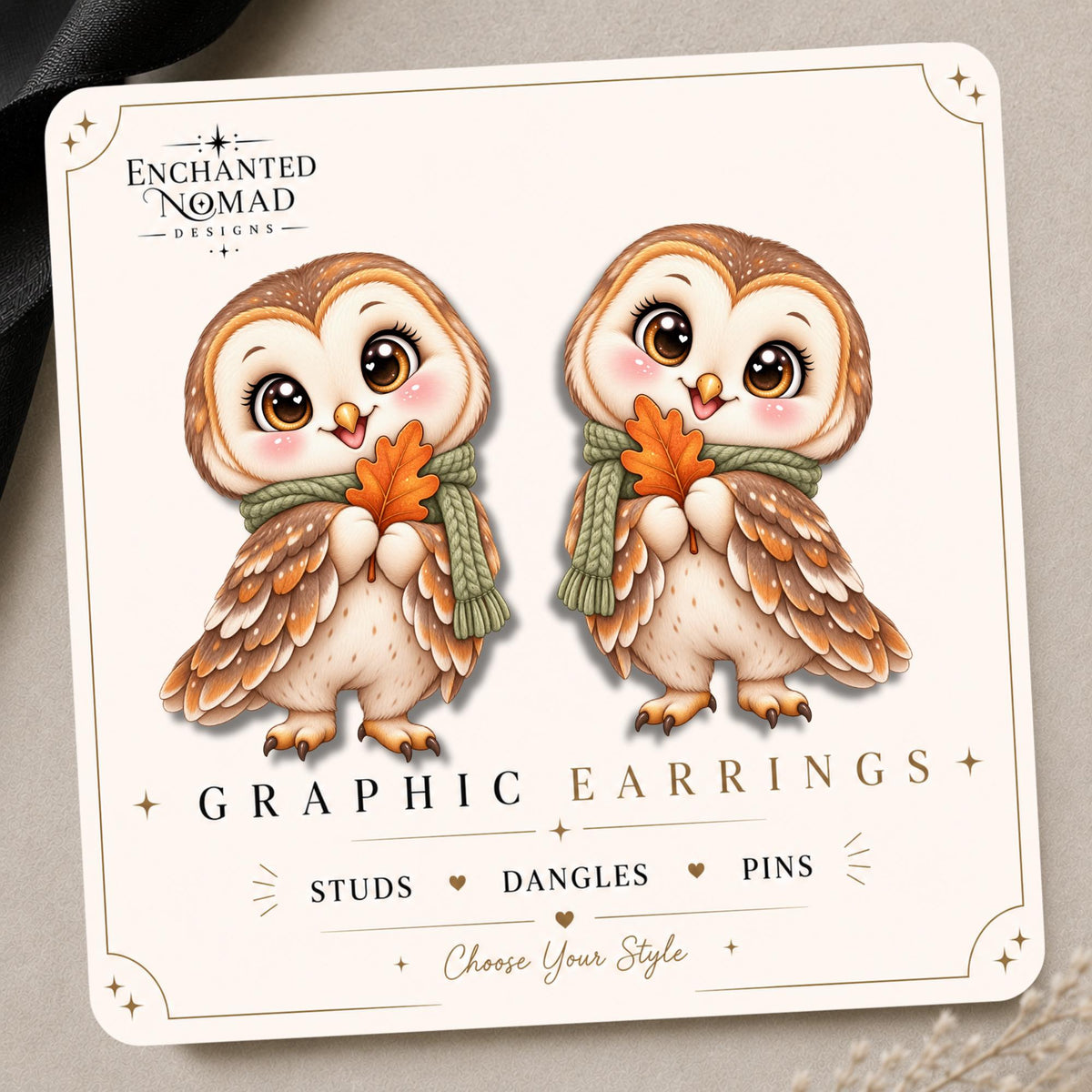 Autumn owl with a sage green scarf and orange leaf on the tilted Enchanted Nomad Designs display card