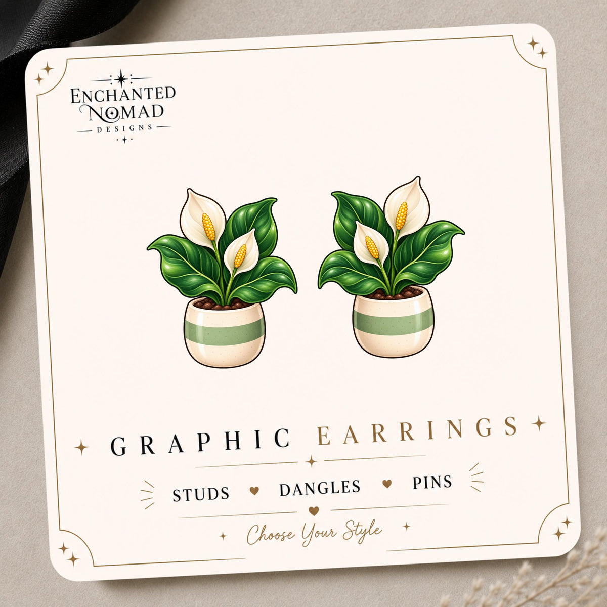 Peace Lily graphic earrings and pins on a display card
